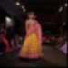 Photographie du défilé d'une mannequin avec robe drapée sur un podium